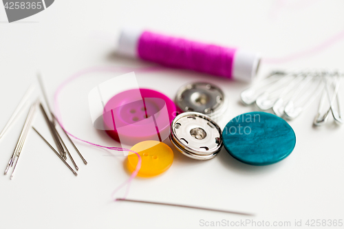 Image of sewing buttons, needles, pins and thread spool