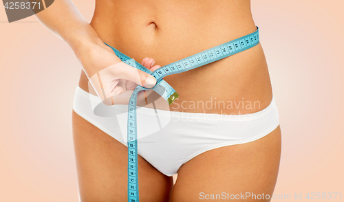 Image of close up of woman body with measure tape on waist