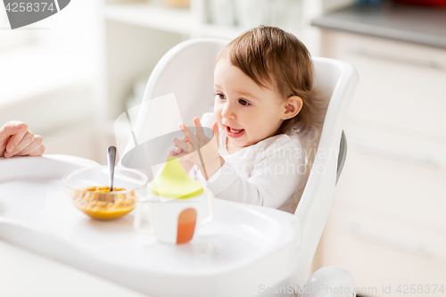 Image of happy baby girl with food and drink eating at home