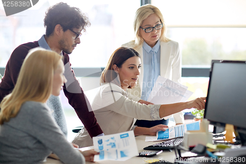 Image of happy business team with computer in office