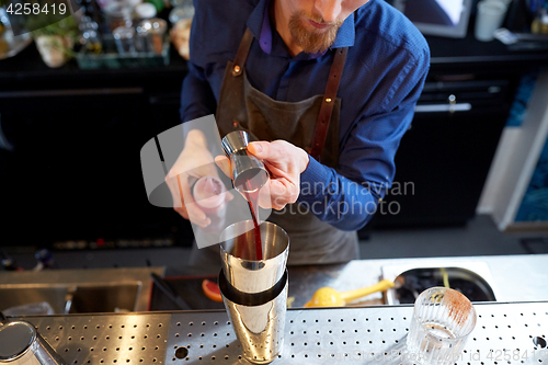 Image of bartender with shaker preparing cocktail at bar