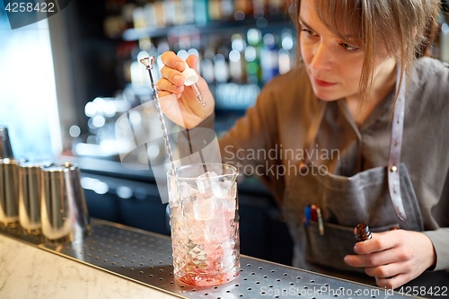 Image of bartender adding essence to cocktail glass at bar