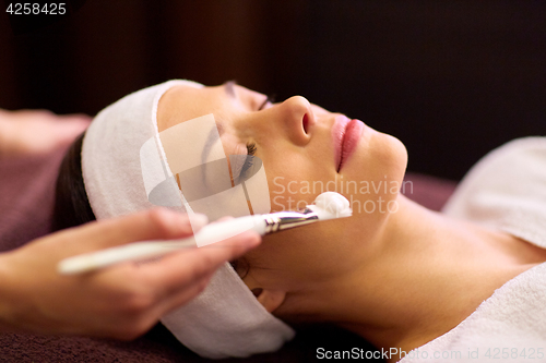 Image of beautician applying facial mask to woman at spa