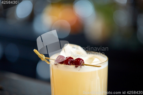 Image of close up of cocktail glass with cherries at bar
