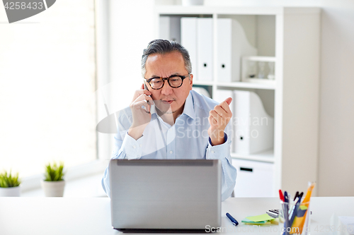 Image of businessman with laptop calling on smartphone