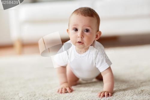 Image of little baby in diaper crawling on floor at home