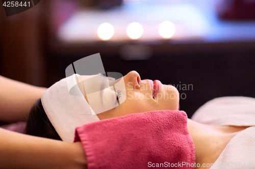 Image of woman having face massage with terry gloves at spa