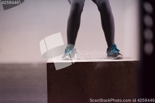 Image of black woman is performing box jumps at gym