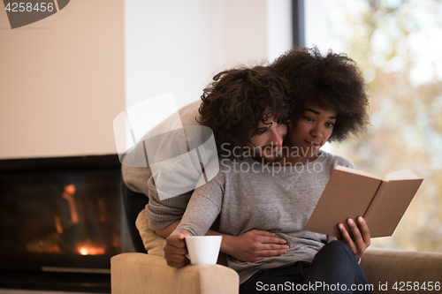 Image of multiethnic couple hugging in front of fireplace