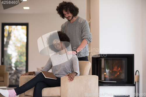 Image of multiethnic couple hugging in front of fireplace