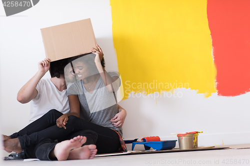 Image of young multiethnic couple playing with cardboard boxes