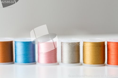 Image of row of colorful thread spools on table