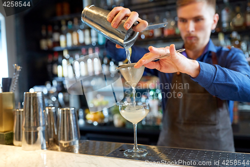 Image of bartender with shaker preparing cocktail at bar