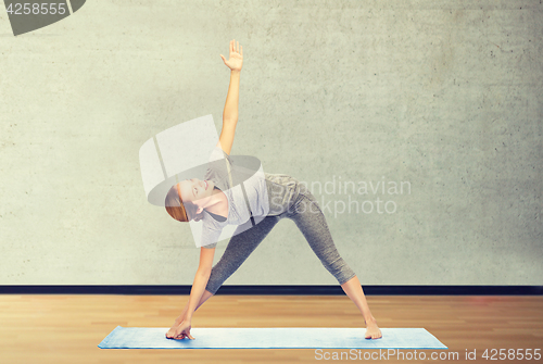 Image of woman making yoga triangle pose on mat