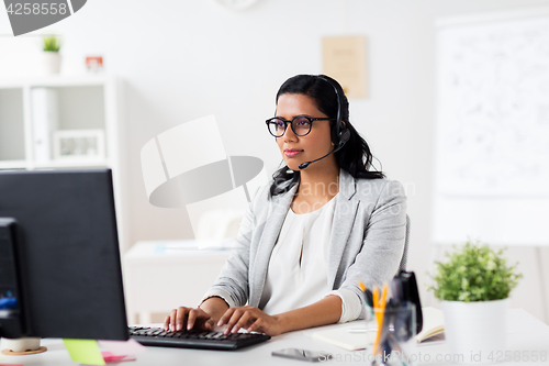 Image of businesswoman with headset and computer at office