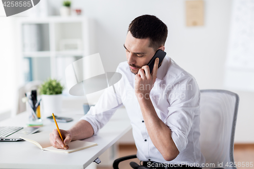 Image of businessman calling on smartphone at office