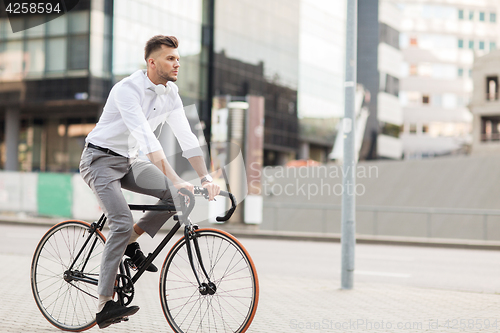 Image of man with headphones riding bicycle on city street