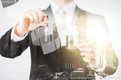 Image of close up of businessman holding keys and house