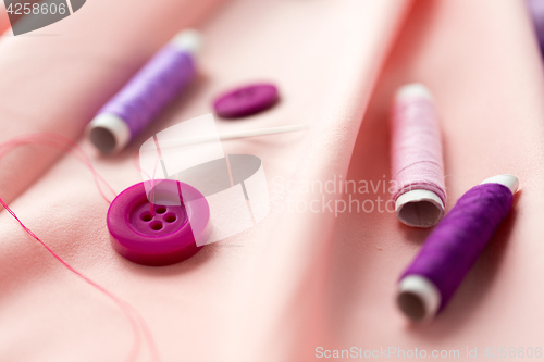 Image of sewing buttons, spools of thread and cloth