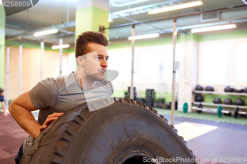 Image of man doing strongman tire flip training in gym