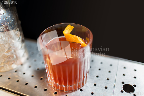 Image of glass with cocktail and orange peel at bar counter