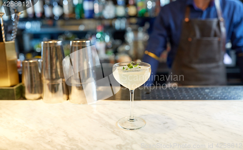 Image of bartender and glass of cocktail at bar