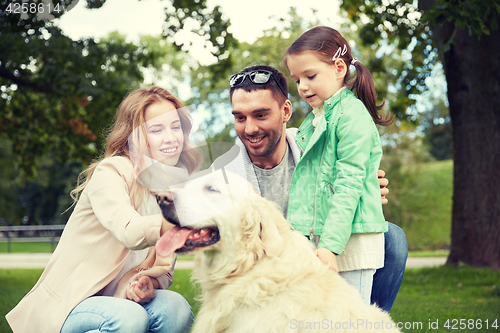 Image of happy family with labrador retriever dog in park