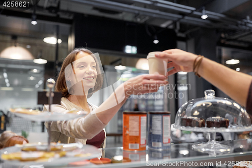 Image of happy woman taking coffee cup from seller at cafe