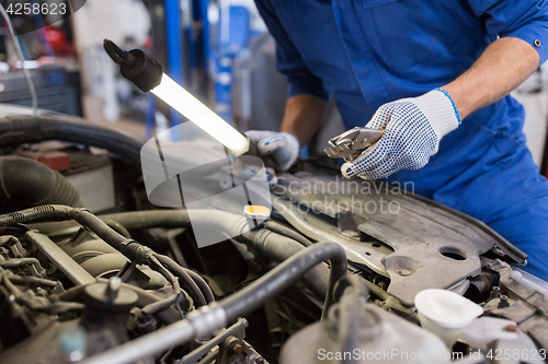 Image of mechanic man with pliers repairing car at workshop