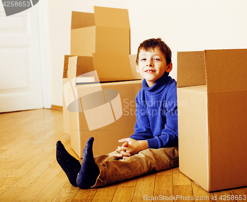 Image of little cute boy in empty room, remoove to new house. home alone emong boxes close up kid smiling