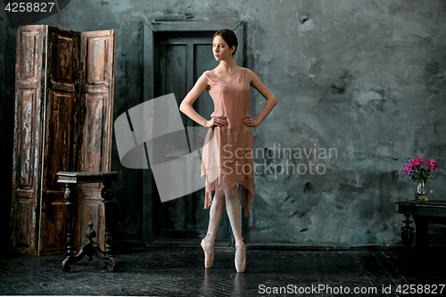 Image of Young and incredibly beautiful ballerina is posing and dancing in a black studio