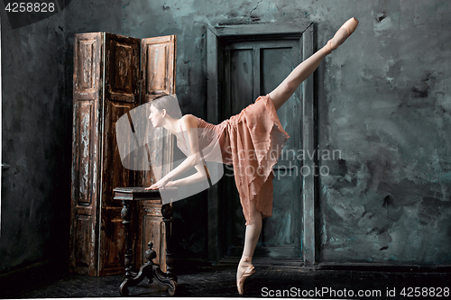 Image of Young and incredibly beautiful ballerina is posing and dancing in a black studio