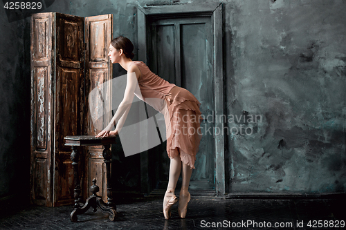 Image of Young and incredibly beautiful ballerina is posing and dancing in a black studio