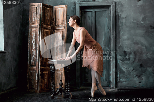 Image of Young and incredibly beautiful ballerina is posing and dancing in a black studio