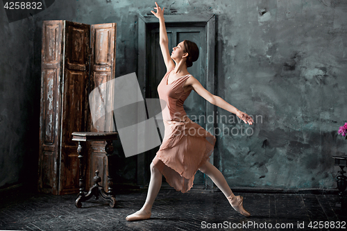 Image of Young and incredibly beautiful ballerina is posing and dancing in a black studio