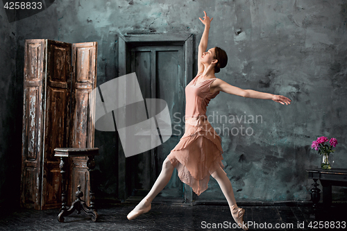 Image of Young and incredibly beautiful ballerina is posing and dancing in a black studio