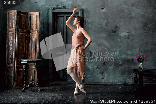 Image of Young and incredibly beautiful ballerina is posing and dancing in a black studio