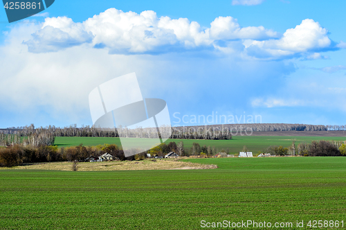 Image of Rural landscape with a green field, clouds and farm