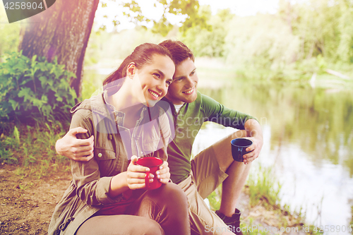 Image of happy couple with cups drinking in nature