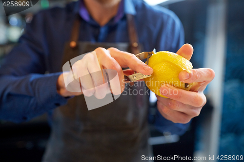 Image of bartender removing peel from lime at bar