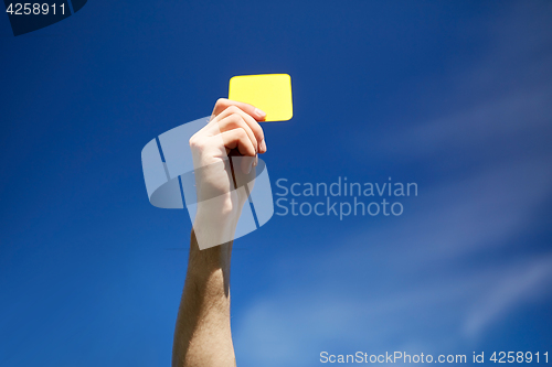 Image of referee on football field showing yellow card