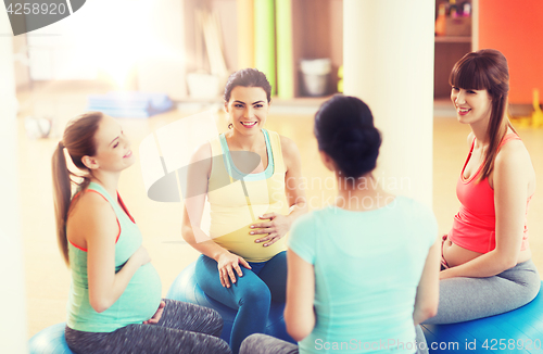 Image of happy pregnant women sitting on balls in gym