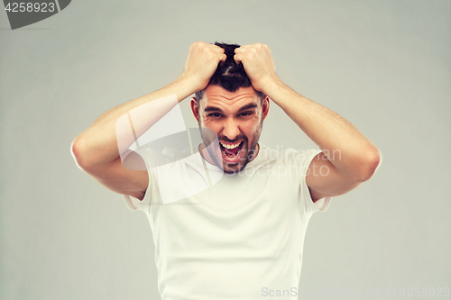 Image of crazy shouting man in t-shirt over gray background