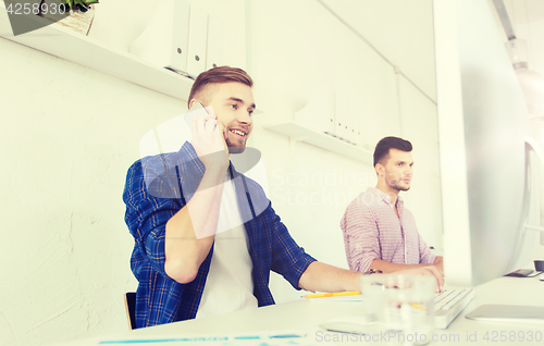 Image of happy creative man calling on cellphone at office