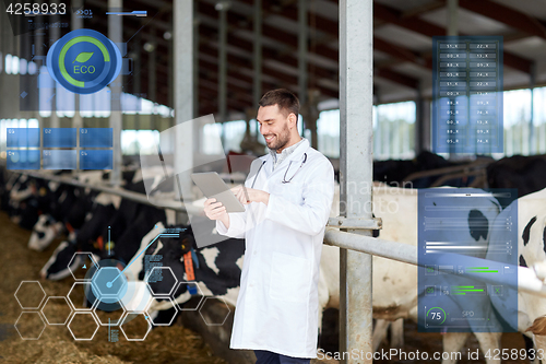 Image of veterinarian with tablet pc and cows on dairy farm