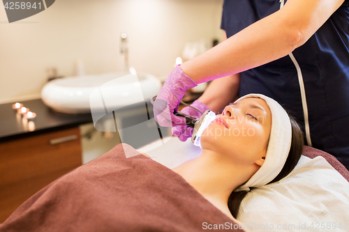 Image of young woman having face microdermabrasion at spa