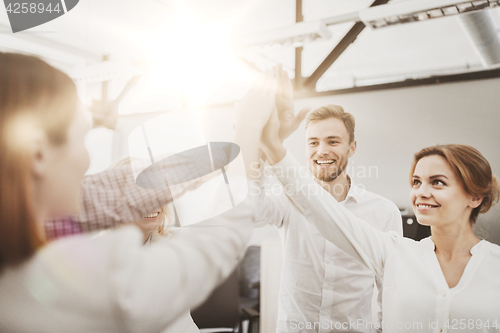 Image of happy business team making high five at office