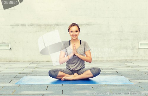 Image of woman making yoga meditation in lotus pose on mat