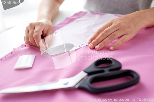 Image of woman with pins stitching paper pattern to fabric