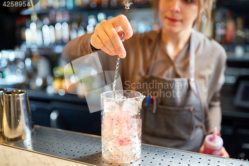 Image of bartender with cocktail stirrer and glass at bar